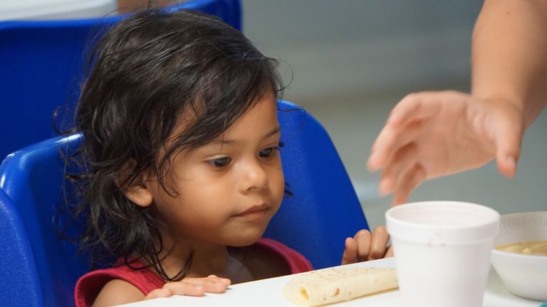 A young girl is given some soup at a migration centre in Texas