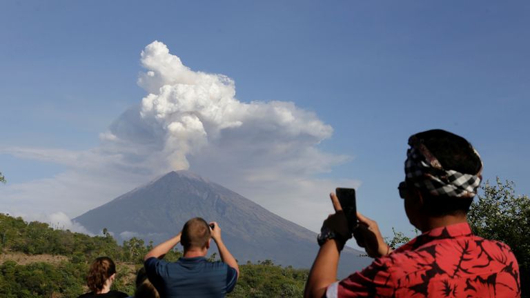 A local guide and foreign tourists take pictures of Mount Agung volcano erupting from Amed, Karangasem Regency in Bali, Indonesia on June 29, 2018. REUTERS/Johannes P. Christo