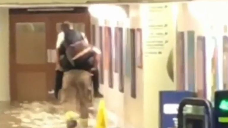 Firefighters give piggybacks at flooded station