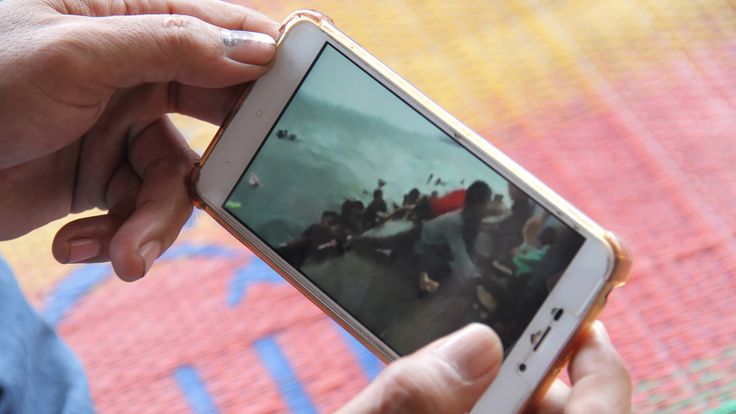 A man holds a phone looking at social media images related to the tragedy as he waits for news on the sunken ferry in Indonesia