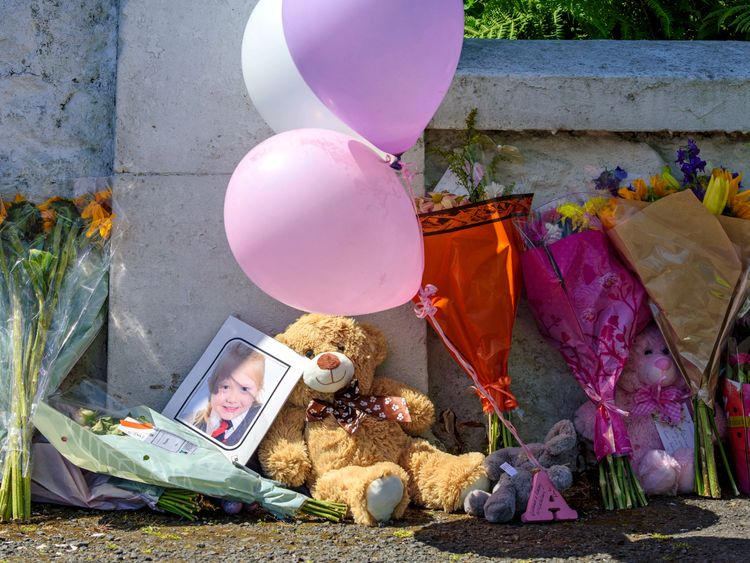 Balloons and a teddy bear are left against a wall