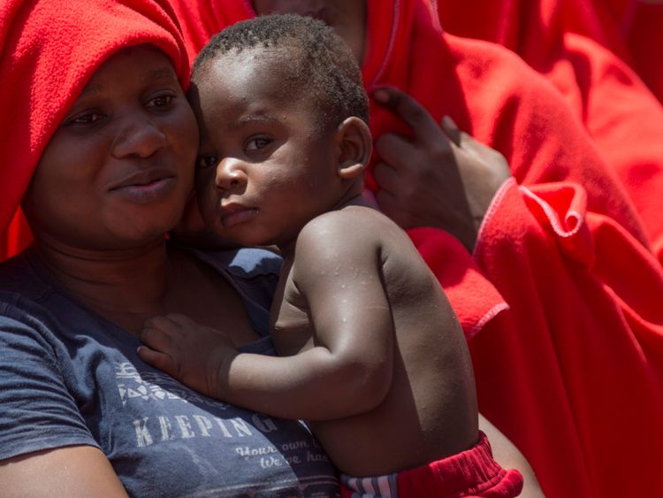 A woman holds her child as a Spanish coast guard boat carrying 110 people rescued from an inflatable boat in the Mediterranean Sea arrives at the harbour of Algeciras