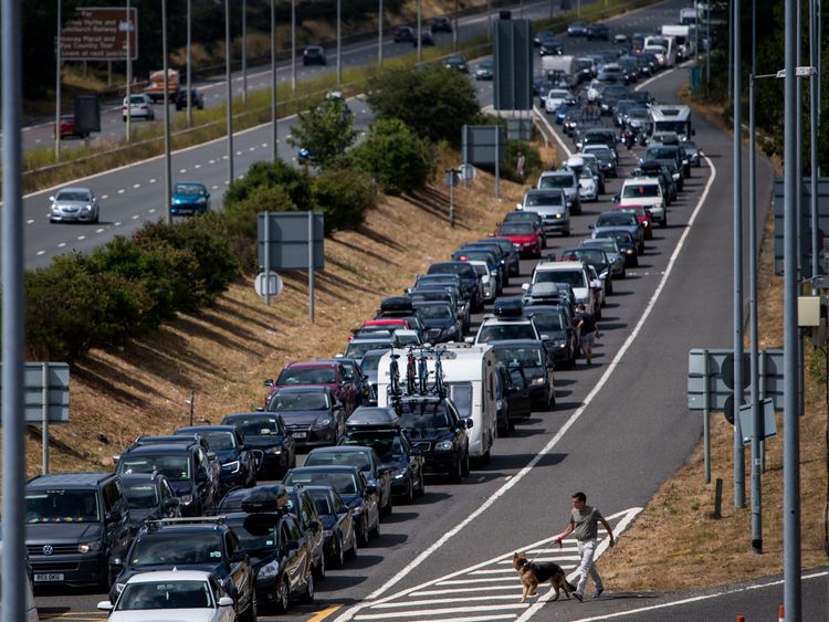 A holidaymaker walks his dog amongst stationary traffic as vehicles queue for Eurotunnel which is experiencing long delays due to extreme weather conditions on July 28, 2018 in Folkestone