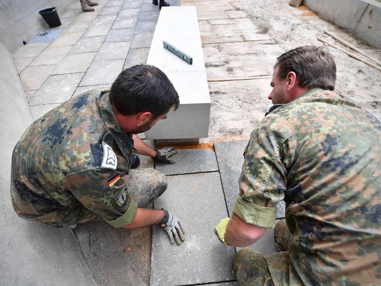Two German soldiers tending to graves on Guernsey. Pic: Allied Rapid Reaction Corps