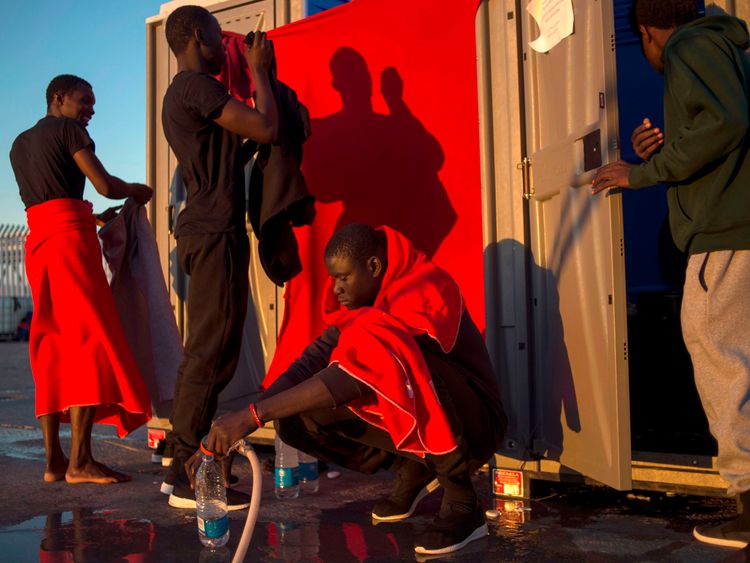 Migrants rescued at sea use mobile bathroom facilities at the harbour of Algeciras