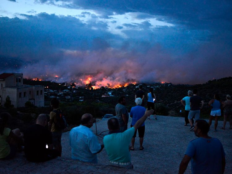 People watch a wildfire in the town of Rafina, near Athens, on July 23, 2018