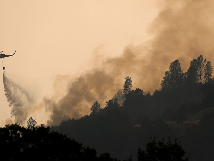 A helicopter drops water on hotspots of the Carr Fire