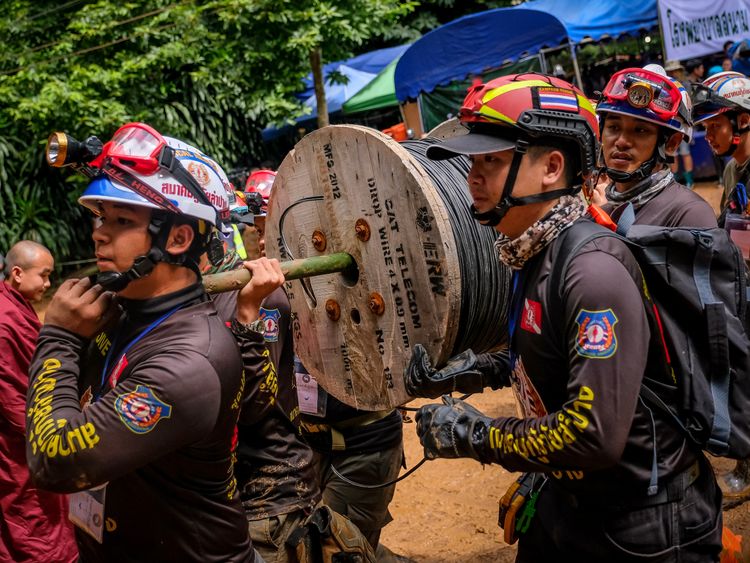 Rescuers carry equipment into the cave complex