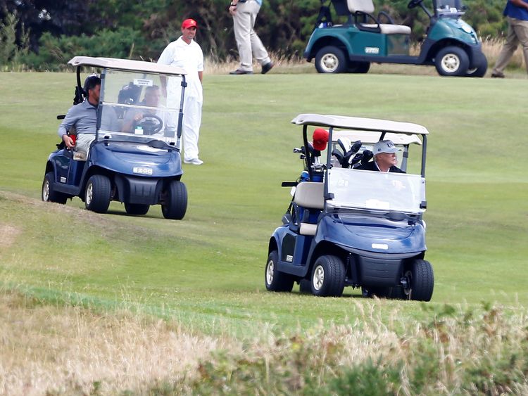 U.S. President Donald Trump drives his golf buggy at his golf resort, in Turnberry,