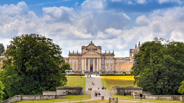 Woodstock, United Kingdom - June 27, 2015: Blenheim Palace, Woodstock, Oxfordshire, England. It is the principal residence of the dukes of Marlborough, and was built between 1705 and 1722. It is being used as a family home, mausoleum and national monument. The palace was also the birthplace of Sir Winston Churchill. Blue sky with clouds, landscaped lawn, green trees and sightseeing tourists entering the palace are in the image.
