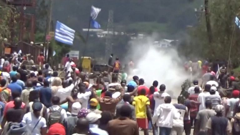 Protesters waving Ambazonian flags as they move forward towards barricades and police amid tear gas in the English-speaking city of Bamenda