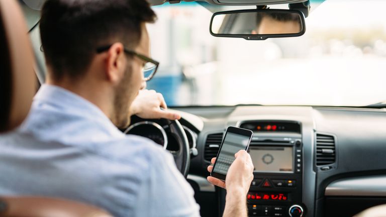 Stock photo of man using phone while driving the car