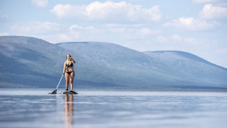 A bikini-clad woman on a surfboard in Finnish Lapland
