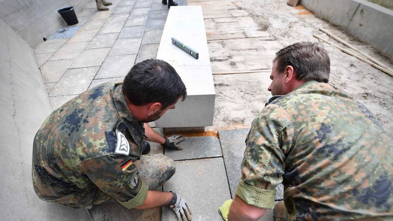 Two German soldiers tending to graves on Guernsey. Pic: Allied Rapid Reaction Corps