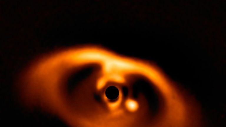 This spectacular image from the SPHERE instrument on ESO&#39;s Very Large Telescope is the first clear image of a planet caught in the very act of formation around the dwarf star PDS 70. The planet stands clearly out, visible as a bright point to the right of the center of the image, which is blacked out by the coronagraph mask used to block the blinding light of the central star. Credit: ESO/A. Müller et al.