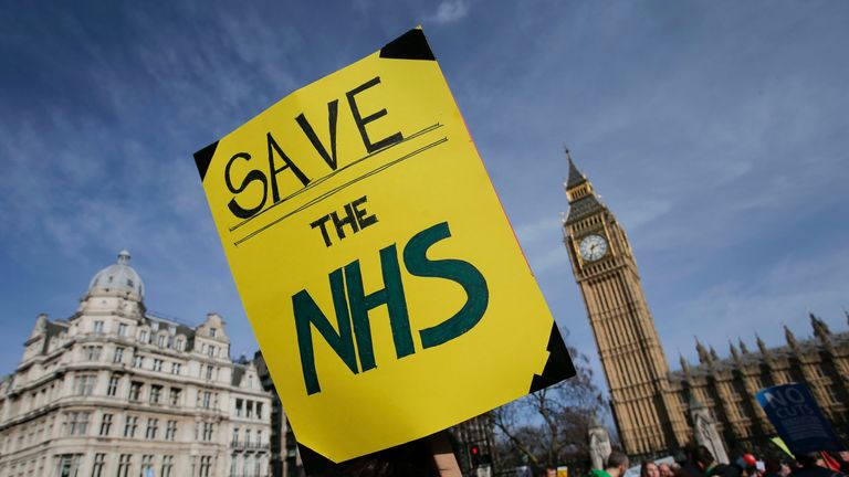 A protester holds a placard in support of the NHS in front of the Elizabeth Tower, also known as Big Ben at the Houses of Parliament during a march against private companies&#39; involvement in the National Health Service (NHS) and social care services provision and against cuts to NHS funding in central London on March 4, 2017