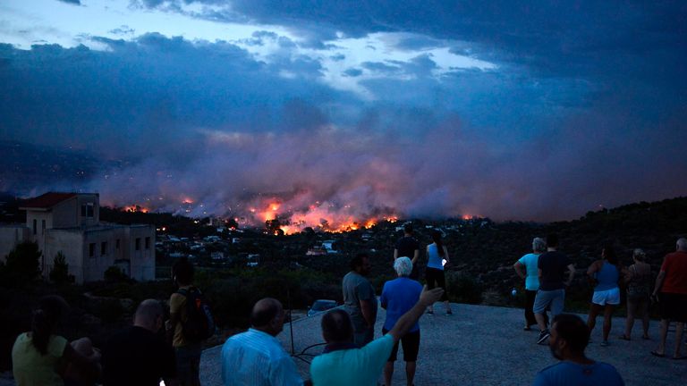 People watch a wildfire in the town of Rafina, near Athens, on July 23, 2018