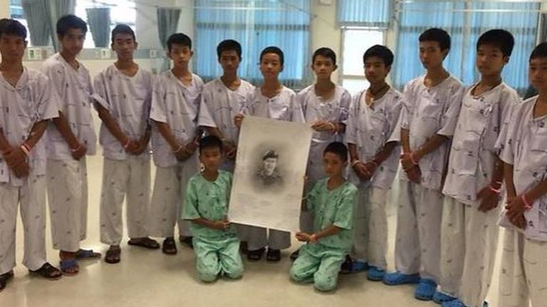 The boys with a picture of Saman Kunan who died during rescue mission