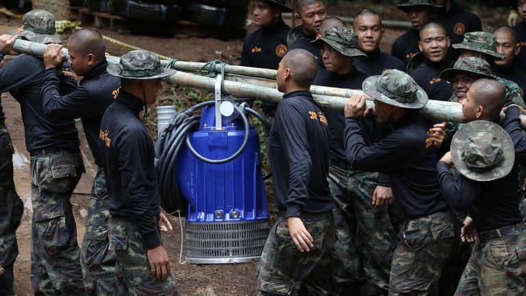 Military personnel carry a water pump as they enter the Tham Luang cave complex