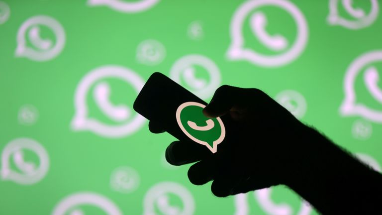 A man poses with a smartphone in front of displayed Whatsapp logo in this illustration September 14, 2017