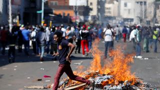 A man runs as supporters of the opposition Movement for Democratic Change party (MDC) of Nelson Chamisa burn barricades in Harare, Zimbabwe