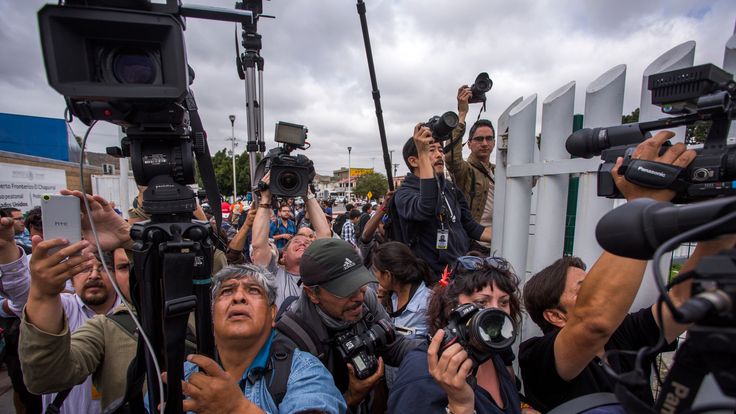 Journalists try to photograph members of a caravan of Central Americans who spent weeks traveling across Mexico as they walk from Mexico onto the U.S. side of the border to ask authorities for asylum on April 29, 2018 in Tijuana