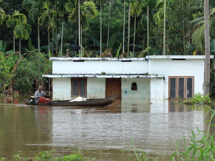 An Indian man rides his boat next to houses immersed in flood waters in Ernakulam district of Kochi, in the Indian state of Kerala