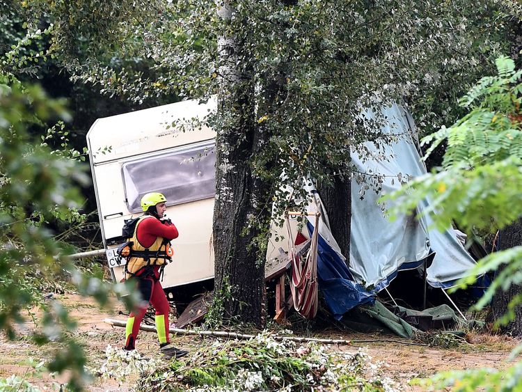 A rescuer walks in front of a damaged caravan in southern France