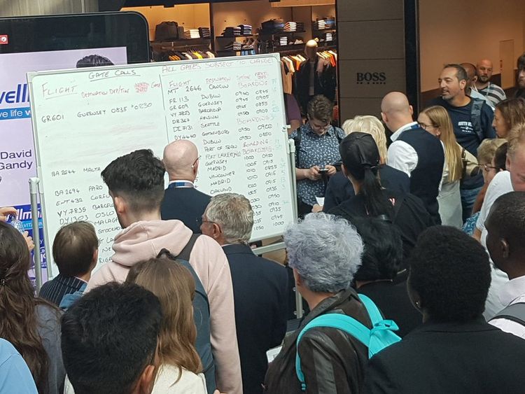 Passengers gather around a whiteboard with the information