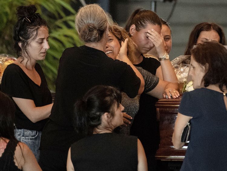 Relatives pray and pay their respects near the coffin of a victim of the Morandi bridge&#39;s collapse, in Genoa, on August 17, 2018. - Italy prepares to pay homage to the victims of the deadly bridge collapse as rescuers use diggers to claw through mountains of rubble in a desperate search for survivors, but some families are reportedly refusing the join the state memorial ceremony. A vast span of the Morandi bridge caved in during a heavy rainstorm in the northern port city of Genoa on August 14, 