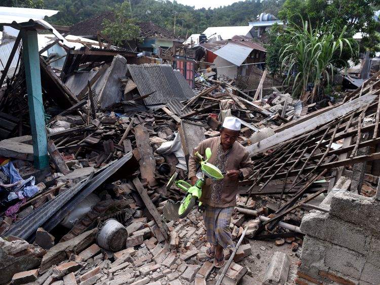 A man carries a small bicycle through the ruins of houses damaged by an earthquake in West Lombok, Indonesia, August 6, 2018 in this photo taken by Antara Foto. Antara Foto/Zabur Karuru / via REUTERS ATTENTION EDITORS - THIS IMAGE WAS PROVIDED BY A THIRD PARTY. MANDATORY CREDIT. INDONESIA OUT.