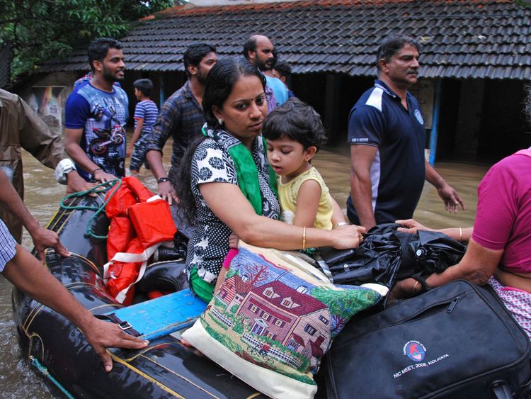 Indian volunteers and rescue personnel evacuate local residents in a boat in a residential area at Kozhikode, in the Indian state of Kerala