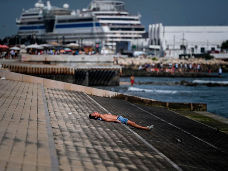 A man sunbathes at Ribeira das Naus in Lisbon on August 3, 2018. - Two men died from heatstroke in Spain as Europe sweltered in a record heatwave today, with temperatures hitting a scorching 45 degrees Celsius in some areas and meteorologists saying only scant relief is in sight in the coming days. The highest temperature ever recorded in Europe was 48 degrees in Athens in 1977, closely followed by 47.3 in Amareleja, Portugal in 2003 as well as in Montoro, Spain last year. (Photo by PATRICIA DE 