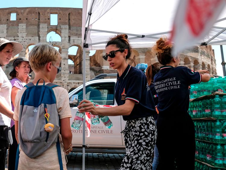 Members of the Italian Civil Protection (Protezione Civile) distribute water bottles to people and tourists in front of the Ancient Colosseum, in central Rome 