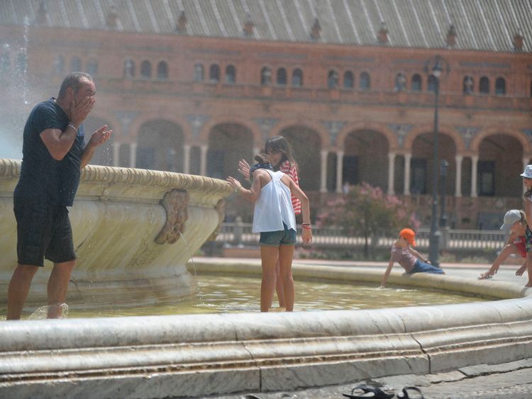People refresh themselves in a fountain at Plaza de Espana, in Sevilla