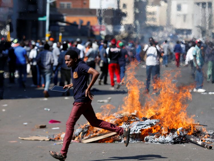 A man runs as supporters of the opposition Movement for Democratic Change party (MDC) of Nelson Chamisa burn barricades in Harare, Zimbabwe