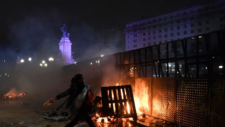A woman hurls a bottle at police outside congress as protesters reacted angrily to the vote