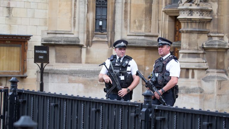 Two armed policemen standing guard outside the Houses of Parliament, Westminster, London England