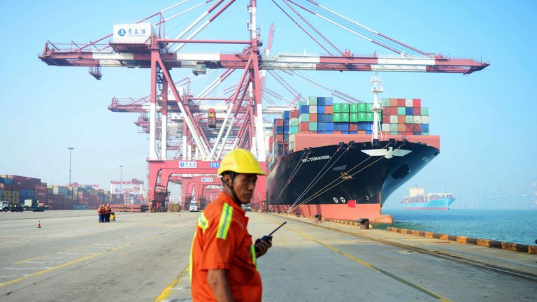 A Chinese worker looks on as a cargo ship is loaded at a port in Qingdao, eastern China&#39;s Shandong province