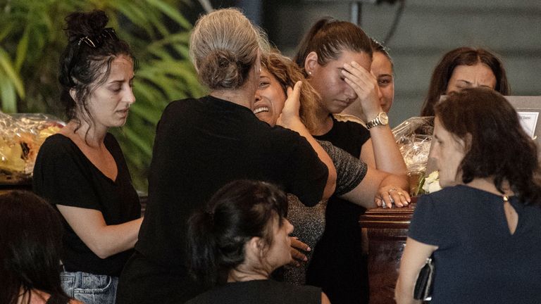 Relatives pray and pay their respects near the coffin of a victim of the Morandi bridge's collapse, in Genoa, on August 17, 2018. - Italy prepares to pay homage to the victims of the deadly bridge collapse as rescuers use diggers to claw through mountains of rubble in a desperate search for survivors, but some families are reportedly refusing the join the state memorial ceremony. A vast span of the Morandi bridge caved in during a heavy rainstorm in the northern port city of Genoa on August 14, 