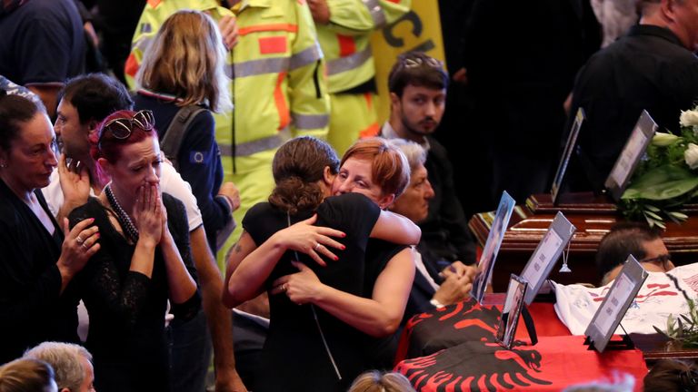 Families hug each other next to the coffins of victims of the Genoa bridge collapse