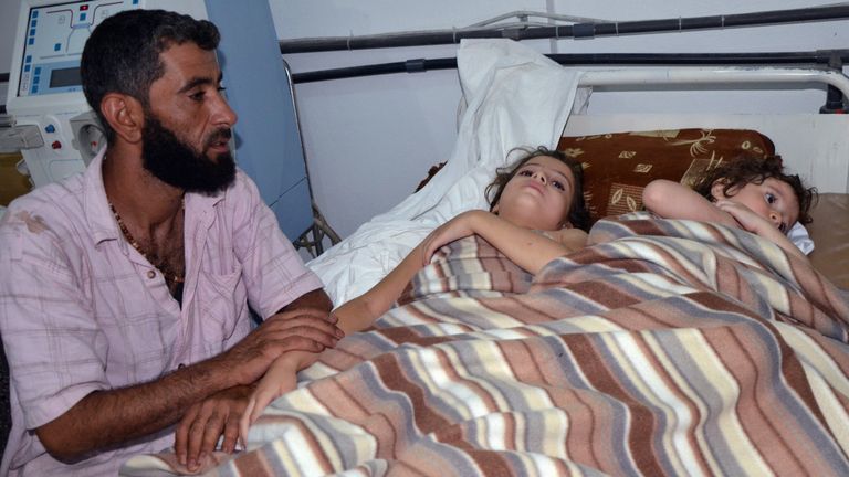 A man sits in a hospital near two children who are believed to have been affected by nerve gas in the 2013 attack in Ghouta