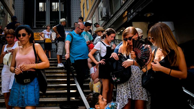 Tourists use fans as they queue to get on Santa Justa lift in downtown Lisbon