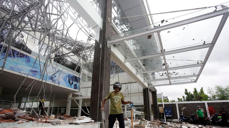A man works in the damage a showroom car building after an earthquake in Bali, Indonesia