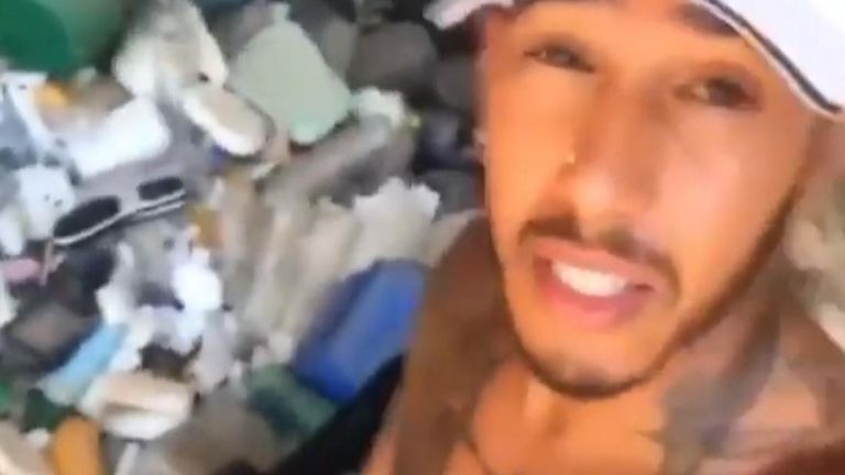 Lewis Hamilton collects plastic waste from a beach while on holiday