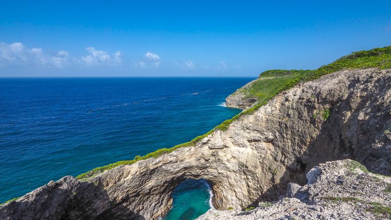 Trou au diable (Devil&#39;s hole), ancient natural arch in the cliffs of Marie Galante, turquoise caribbean sea.