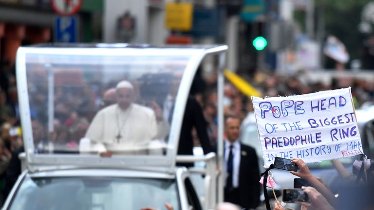 A protester holds a banner as Pope Francis drives by during his visit in Dublin, Ireland