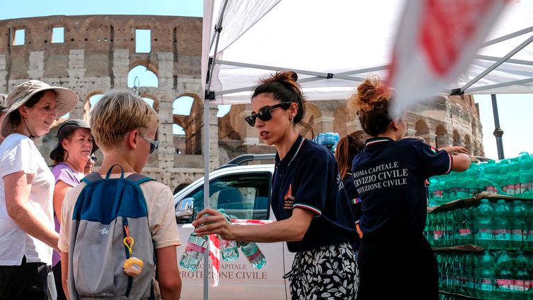 Members of the Italian Civil Protection (Protezione Civile) distribute water bottles to people and tourists in front of the Ancient Colosseum, in central Rome 