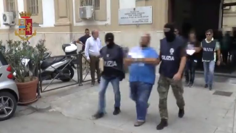 A member of the gang is led away by police in Palermo