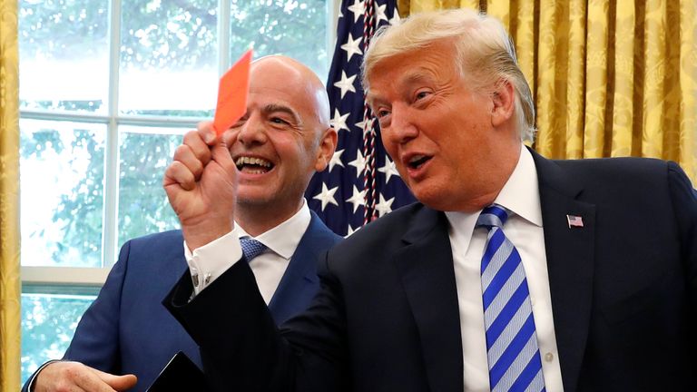 President Donald Trump holds a red card as he meets with FIFA President Gianni Infantino in the Oval Office